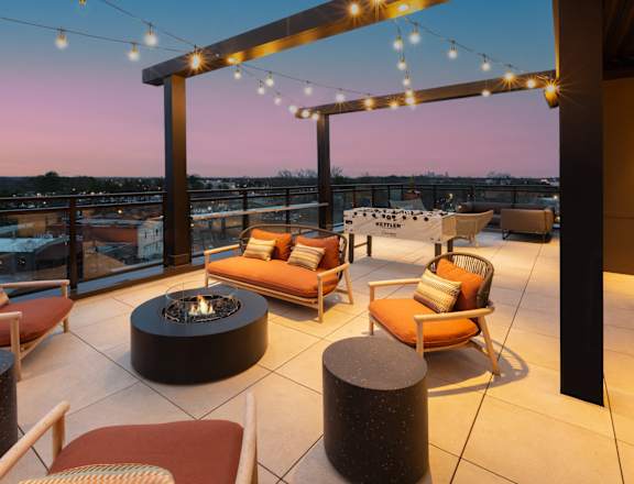 a rooftop terrace with chairs and tables and a fire pit