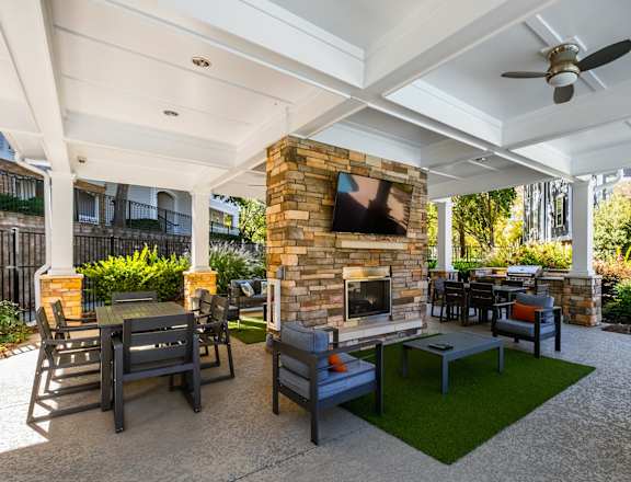 a patio with a fireplace and tables and chairs and a television