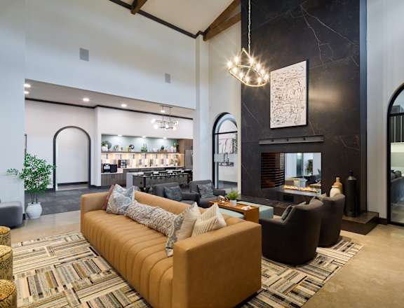 A living room with a brown sofa and a chandelier.