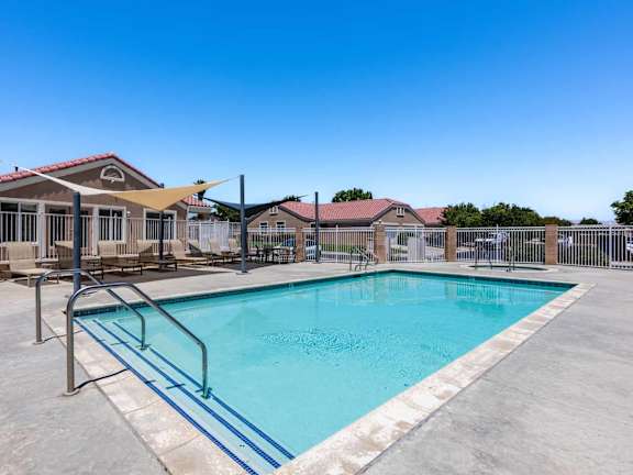 A swimming pool surrounded by a fence and a building in the background.