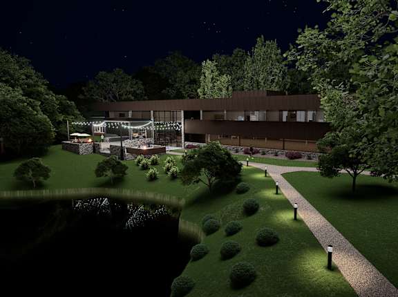 A nighttime view of a building with a well-lit pathway leading to the entrance.