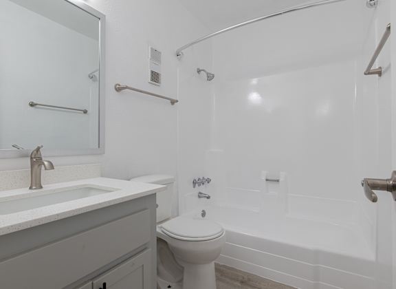 A white toilet sits next to a white sink in a white bathroom. at Sofia Apartments, Tempe, AZ, 85283