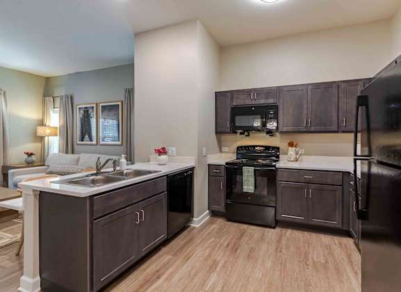 A kitchen with black appliances and brown cabinets.