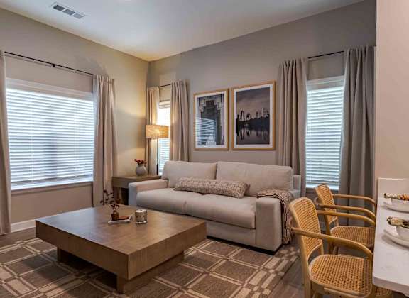 A living room with a grey couch, a coffee table, and a dining table set for two.