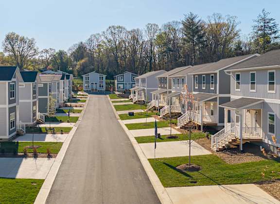 A long road in a residential neighborhood with houses on both sides.