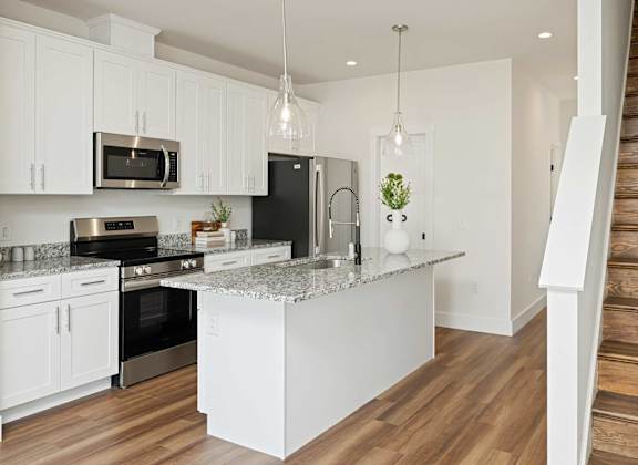 A kitchen with white cabinets and a granite countertop.