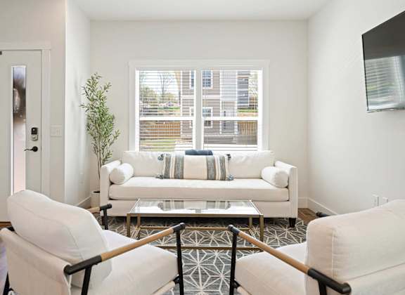 A white chair is in front of a glass coffee table.