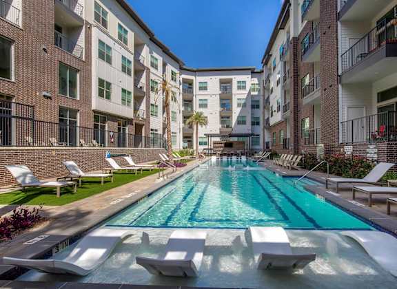 an outdoor pool with lounge chairs and an apartment building