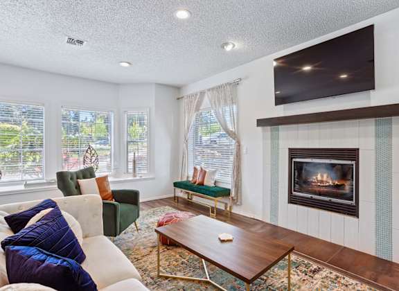 A living room with a fireplace and a television mounted above it.