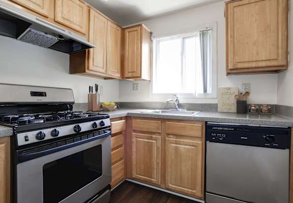 A kitchen with a stove, sink, and cabinets.