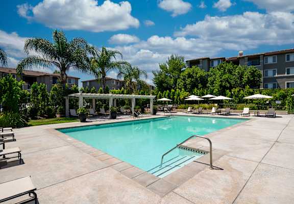 A swimming pool surrounded by lounge chairs and umbrellas.