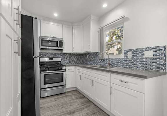 a kitchen with white cabinets and stainless steel appliances