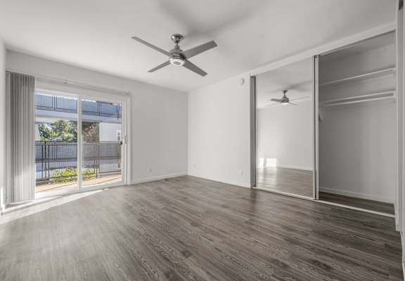 an empty living room with a large window and a ceiling fan