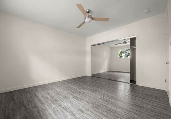 an empty living room with white walls and a ceiling fan