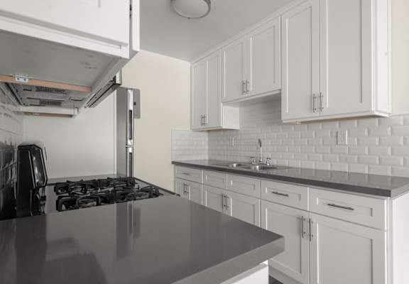 a kitchen with white cabinets and black counter tops