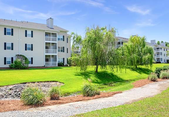 A white apartment building with a green lawn in front.