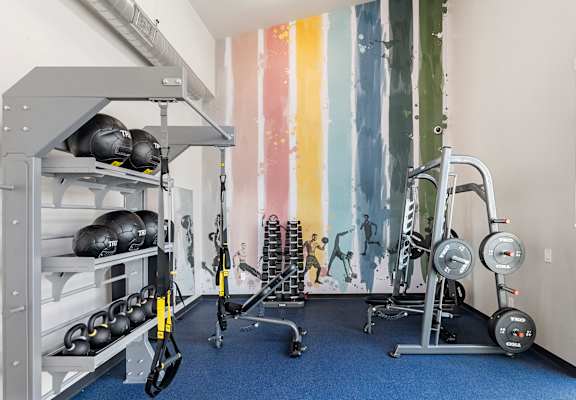 a workout room with weights and a colorful wall mural at SECOND AVE COMMONS | BRAND-NEW, Mesa, Arizona