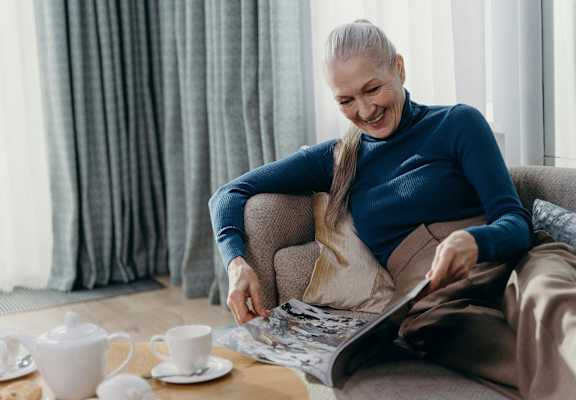 a woman sitting on a couch looking at a magazine