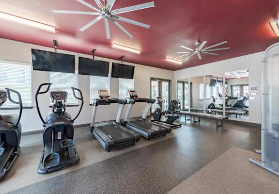 A gym with treadmills, elliptical machines, and other exercise equipment.