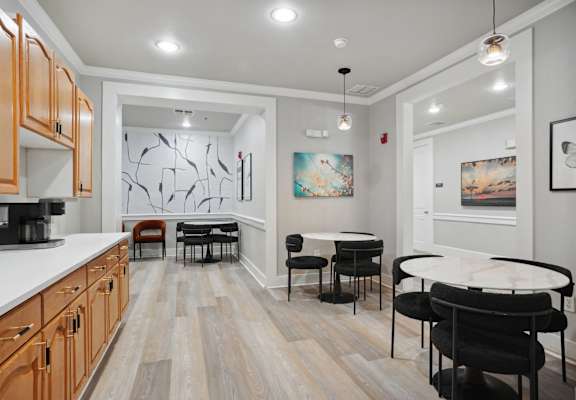 a dining room with a round table and chairs and a kitchen with a sink