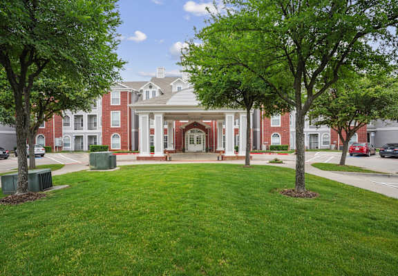 a large building with a lawn and trees in front of it