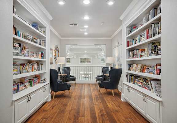 a living room filled with bookshelves and chairs