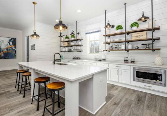 a white kitchen with a large island and bar stools