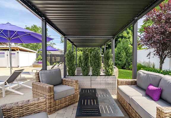 A patio with a wicker sofa, chairs, and a table.