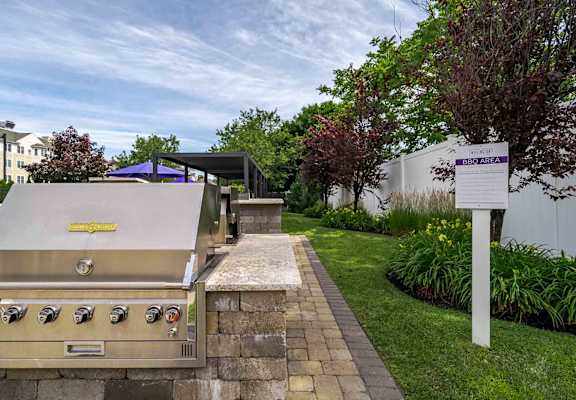 A stainless steel grill with a yellow sticker on it is on a patio.
