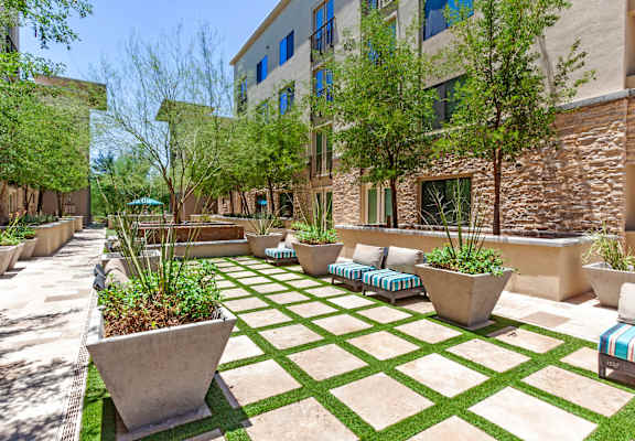 A courtyard with a green lawn and concrete planters.