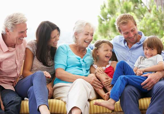 A group of people of different ages are sitting on a couch.