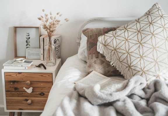 a bedroom with a bed and a nightstand with a book and a pillow