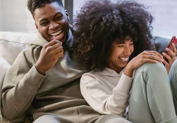 a man and woman sitting on a couch looking at a cell phone