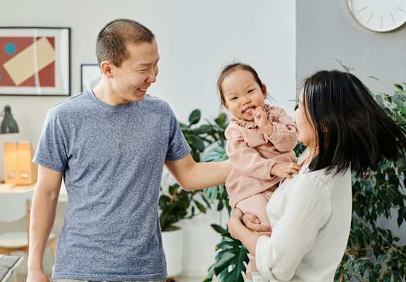 A man and woman holding a baby in a living room