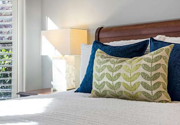 a bedroom with a bed with colorful pillows and a window