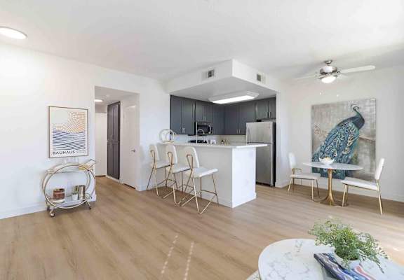 A kitchen with a white island and white chairs.