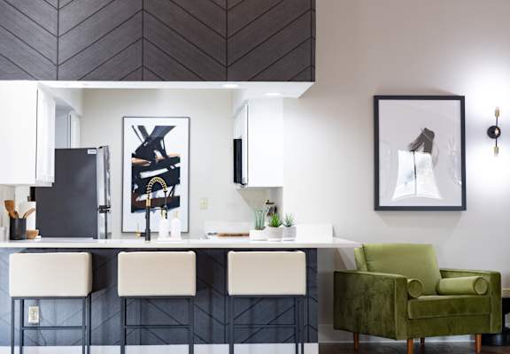 Kitchen with white cabinets and a black and white kitchen island with three white chairs at Bradford Ridge Apartments, Bloomington, IN