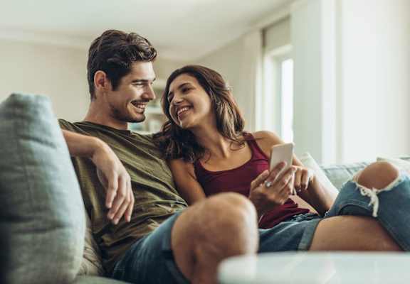 A couple is sitting on a couch at Jolt Apartments, Las Vegas, NV