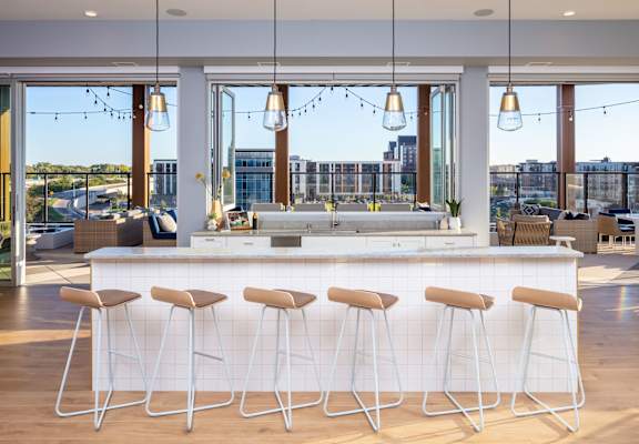a kitchen with a bar and stools in front of a window with a view of a