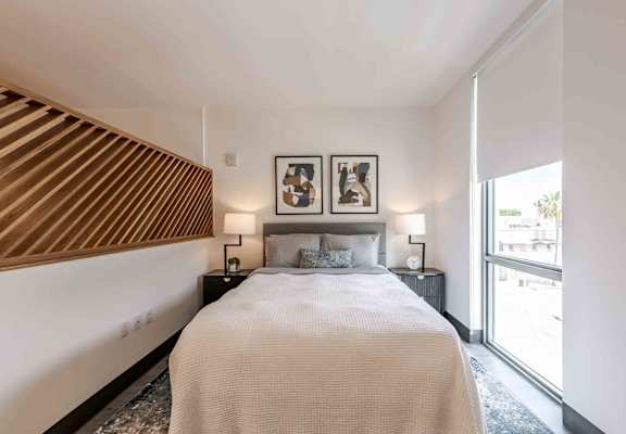 A bedroom with a large bed and two pictures on the wall.