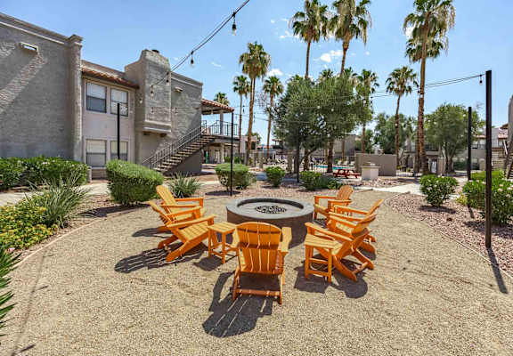 A patio with a fire pit and chairs.