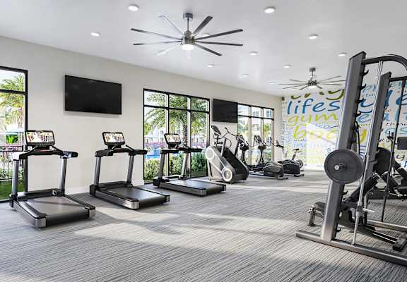 a gym with cardio equipment and windows in a building
