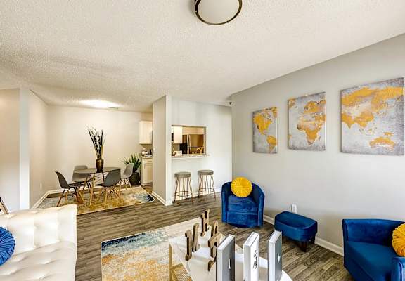A living room with a white couch and blue chairs at Sedgefield Square Apartments, North Carolina, 27407
