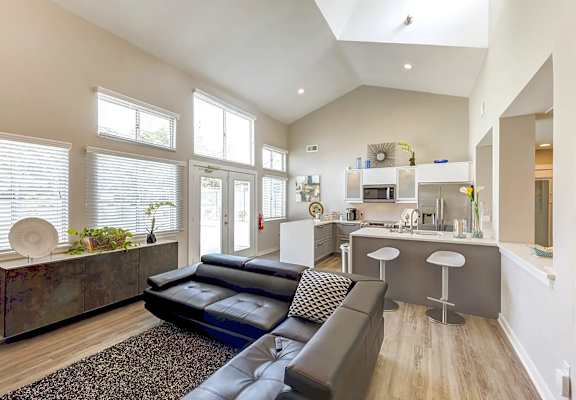 A modern living room with a black couch and a wooden cabinet at Sedgefield Square Apartments, North Carolina, 27407
