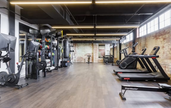 a gym with weights and cardio machines and a brick wall at The Mill at Prattville, Alabama
