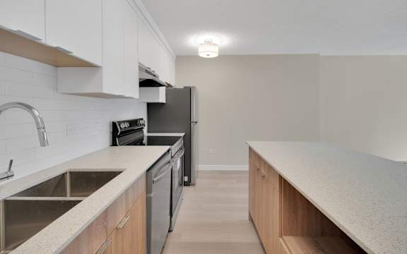A kitchen with a black refrigerator and stove top oven.