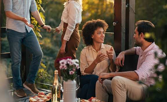 a group of people sitting around a table with food and drinks