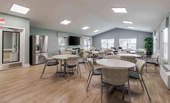 A spacious room with tables and chairs and a television.