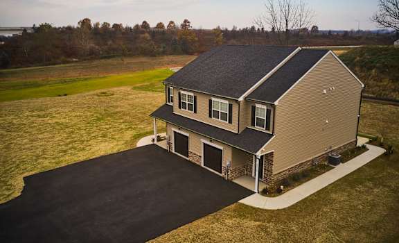 a home with a gray roof and a brown house with a field in the background