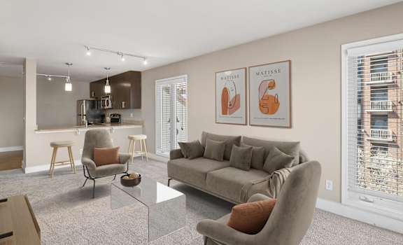 a living room with a couch coffee table and chairs and a kitchen in the background